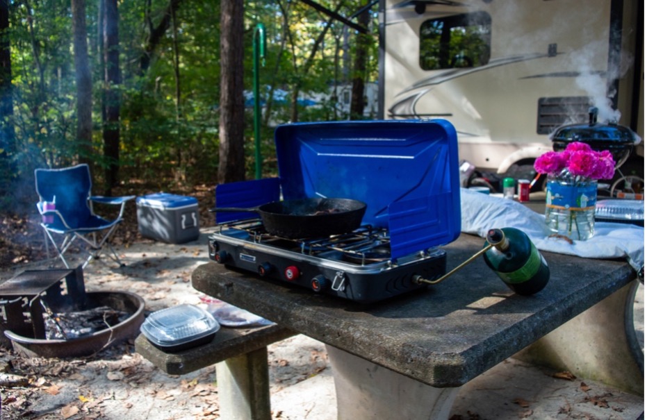 A camper with a grill and a bottle on a picnic table
