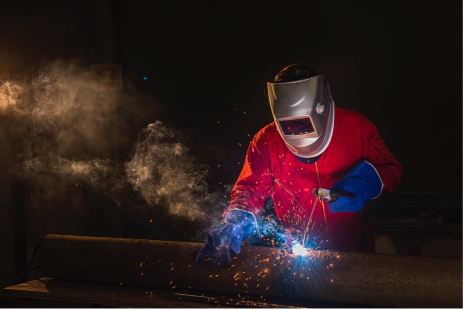 A person wearing a mask and gloves welding a piece of metal
