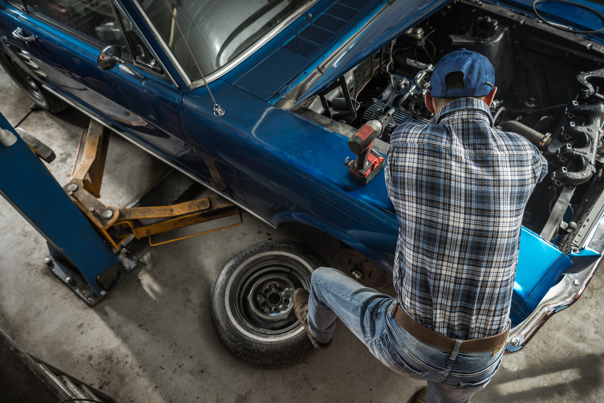 Caucasian Car Mechanic in His 40s Performing Classic Car Engine Repairs. Automotive Industry Theme.