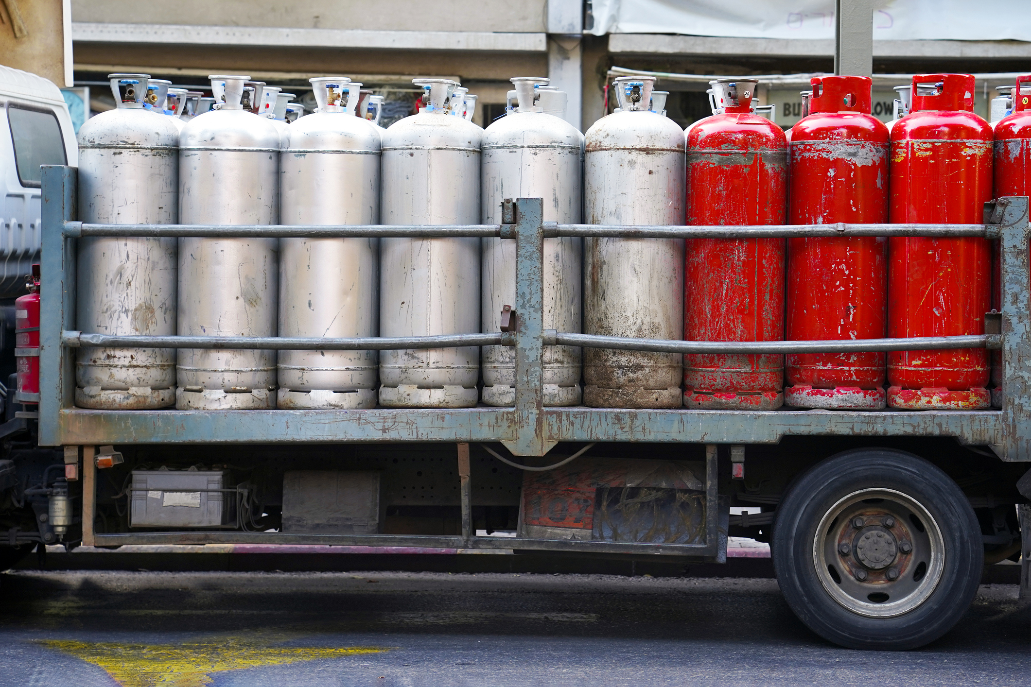 Truck with gas cylinders on the road. Many red and grey gas cylinders transported in car.